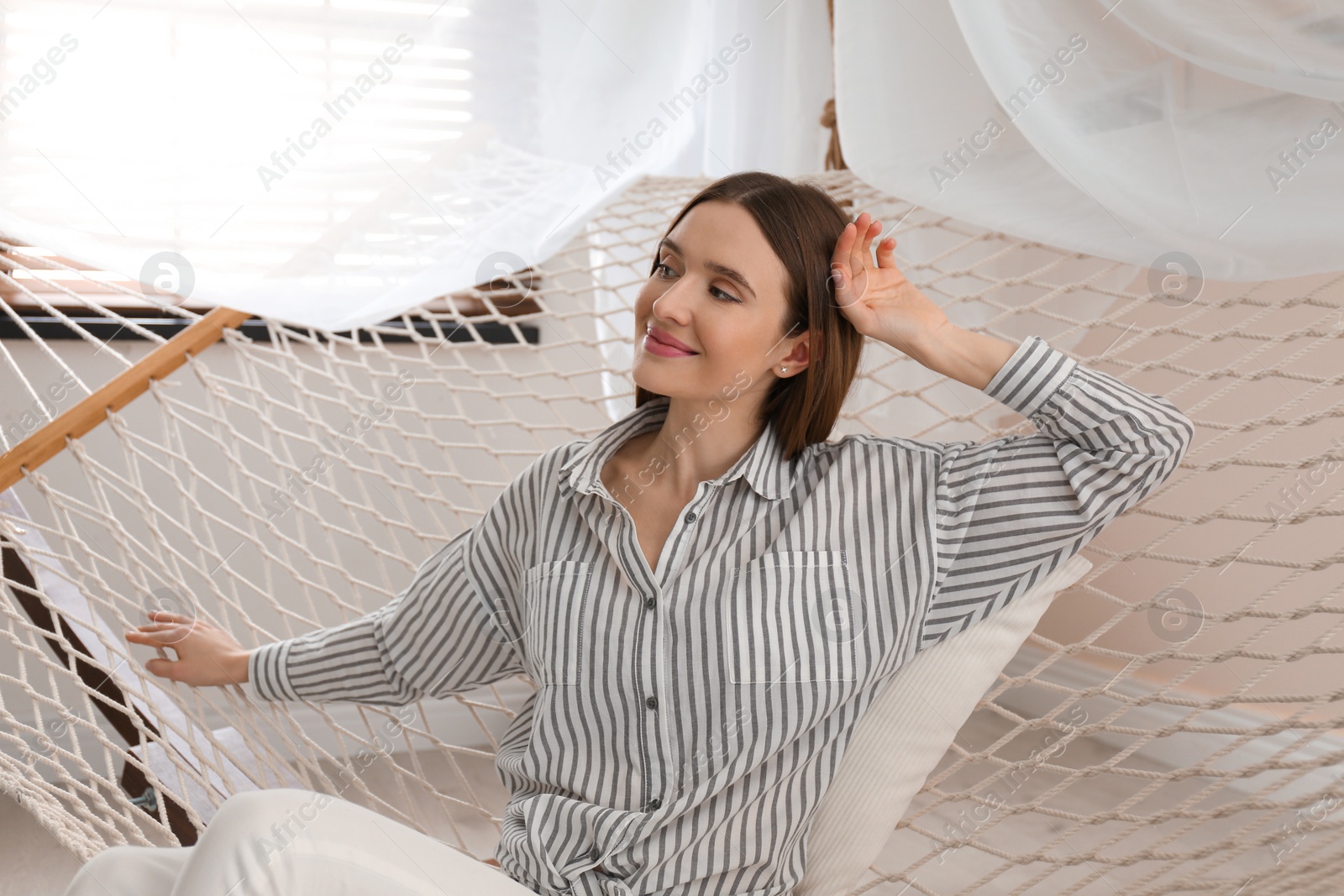 Photo of Happy woman resting in hammock at home
