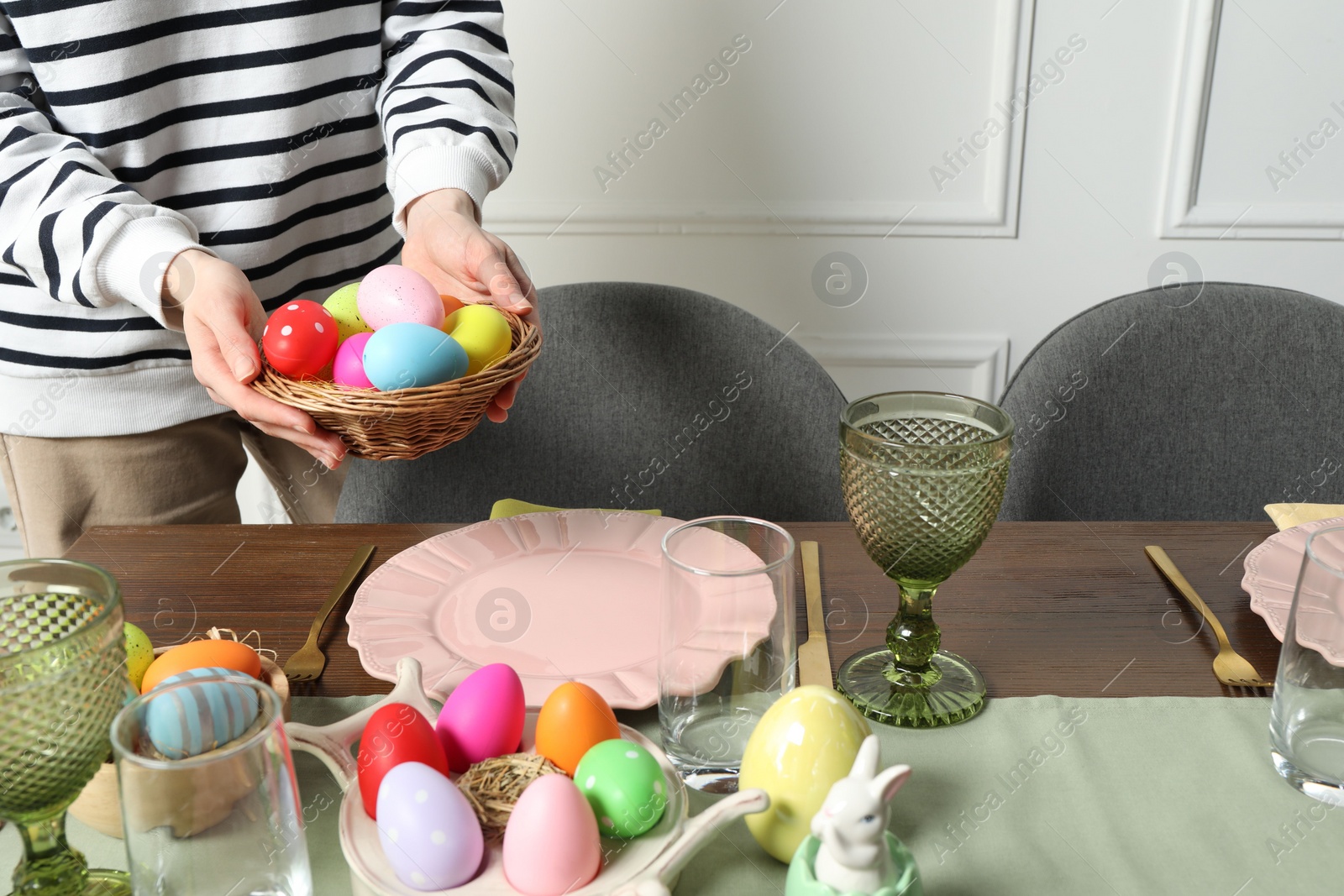 Photo of Woman setting table for festive Easter dinner at home, closeup