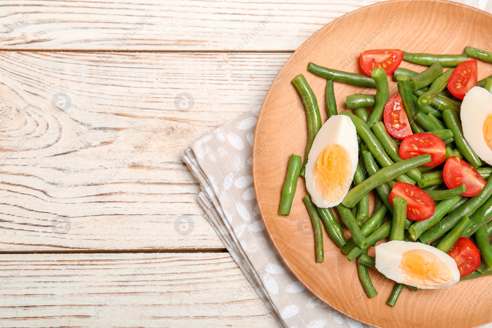 Photo of Plate with tasty green beans, eggs and  tomatoes on wooden table, top view