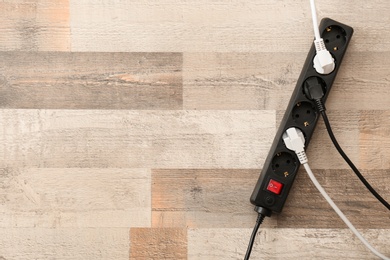 Photo of Extension cord on wooden floor, top view with space for text. Electrician's equipment