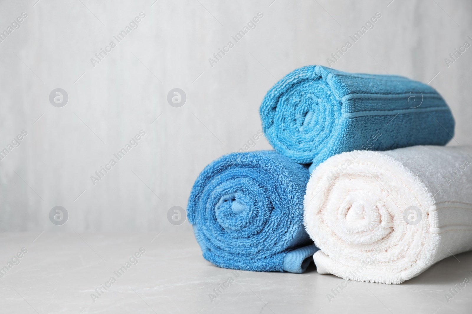 Photo of Rolled bath towels on table. Space for text