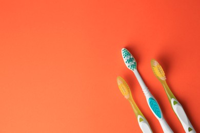 Toothbrushes on orange background, flat lay. Space for text