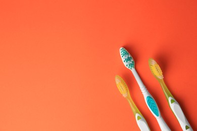 Photo of Toothbrushes on orange background, flat lay. Space for text