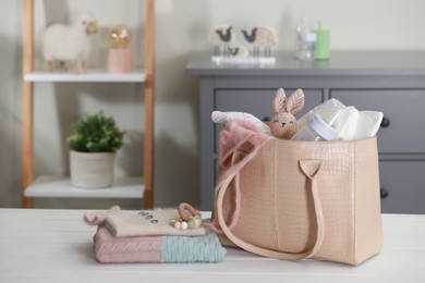 Photo of Mother's bag with baby's stuff on white wooden table indoors