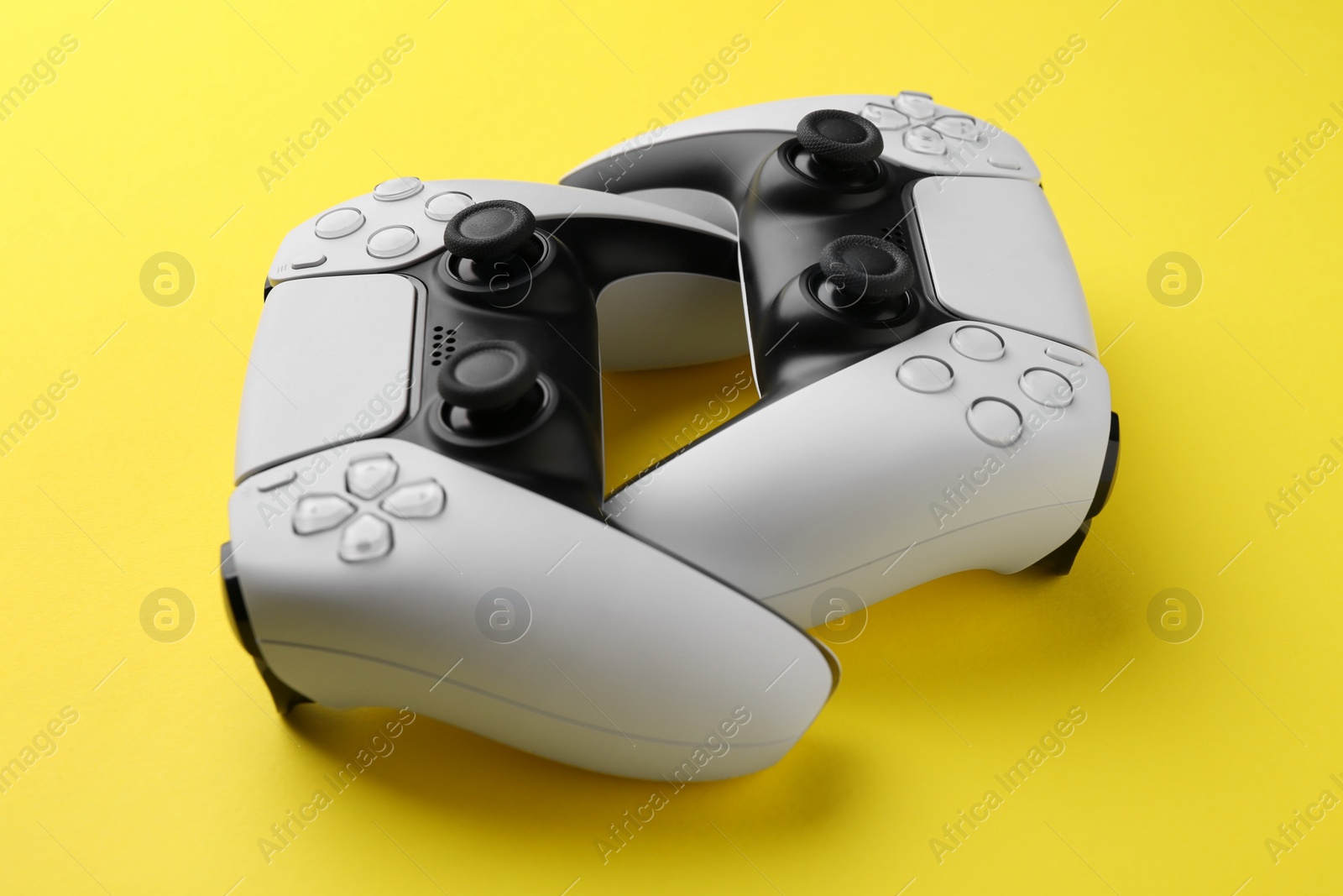 Photo of Two wireless game controllers on yellow background