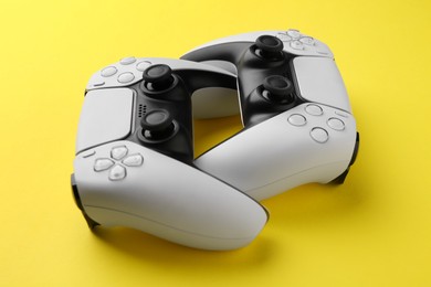 Two wireless game controllers on yellow background