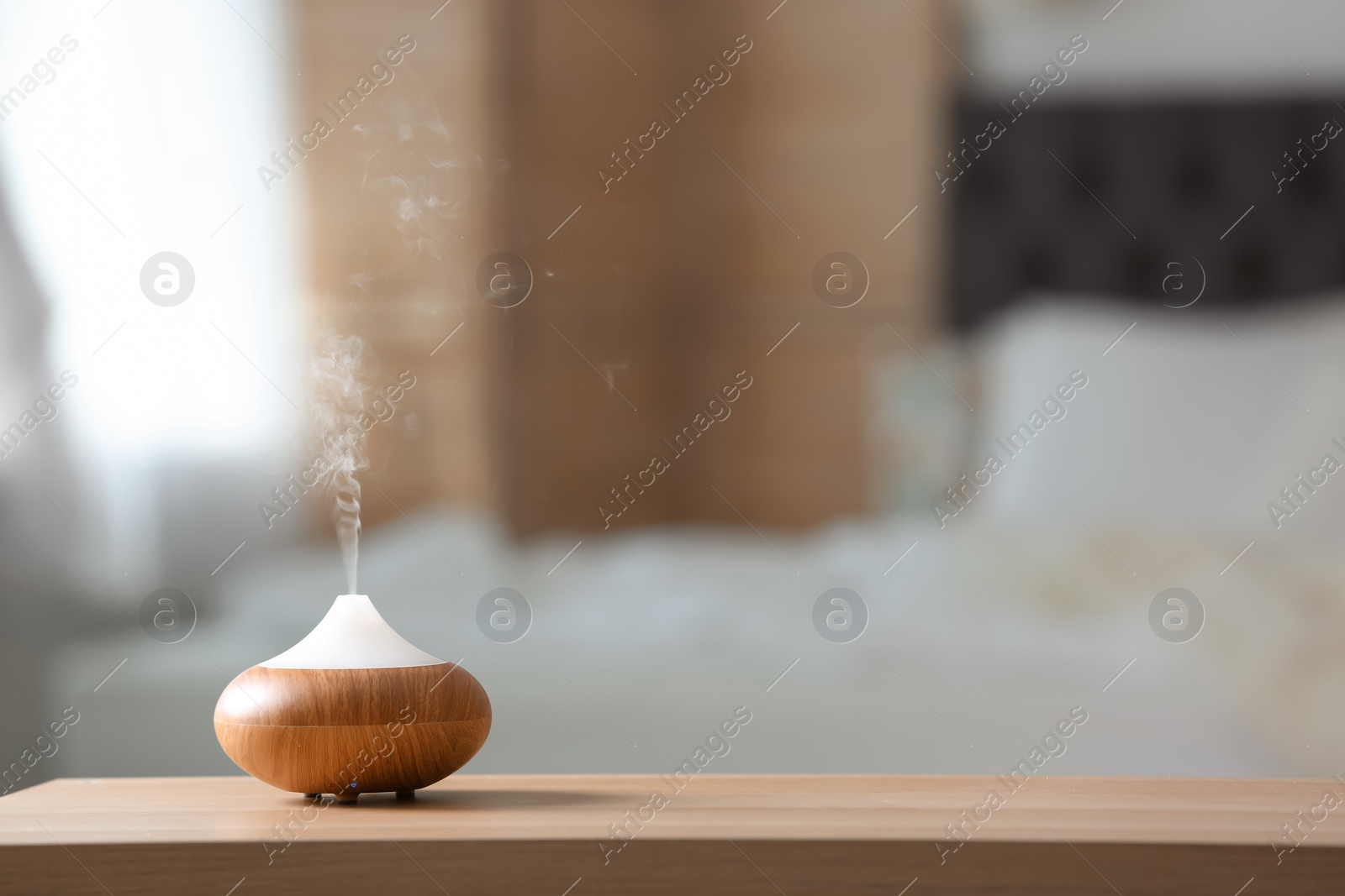 Photo of Aroma oil diffuser lamp on table against blurred background