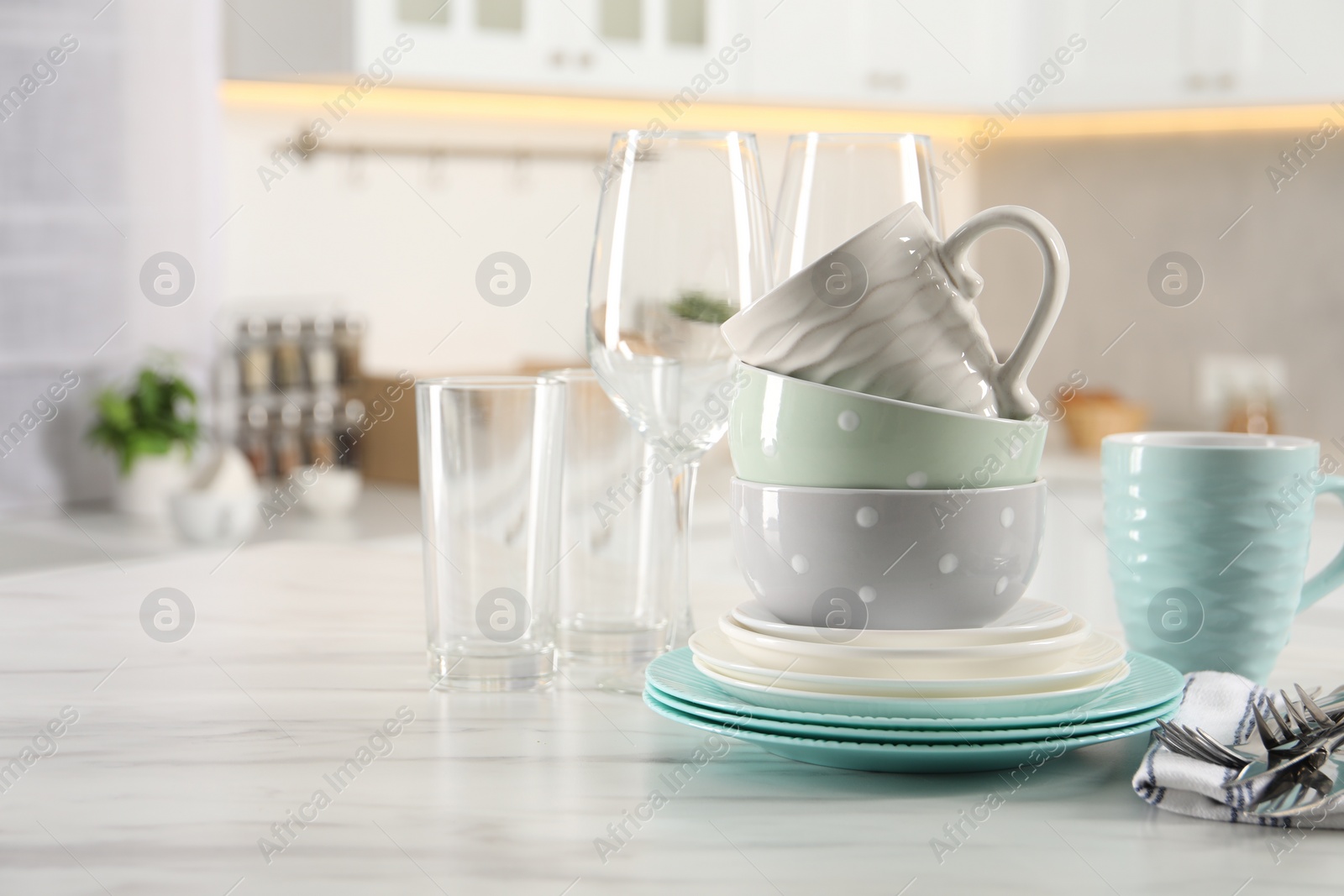 Photo of Many different clean dishware, cutlery, glasses and cups on white marble table in kitchen. Space for text