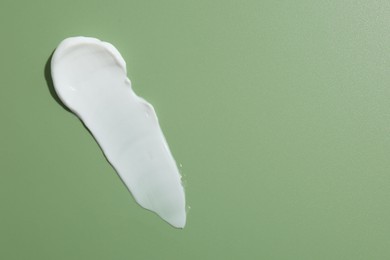 Photo of Sample of face cream on green background, top view. Space for text