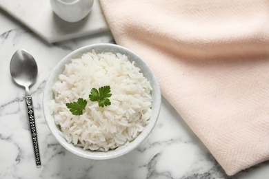 Photo of Bowl of cooked rice with parsley served on table, flat lay. Space for text