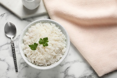 Bowl of cooked rice with parsley served on table, flat lay. Space for text