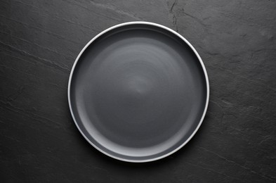 Photo of New dark plate on black table, top view