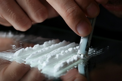 Photo of Drug addict taking cocaine at table, closeup view