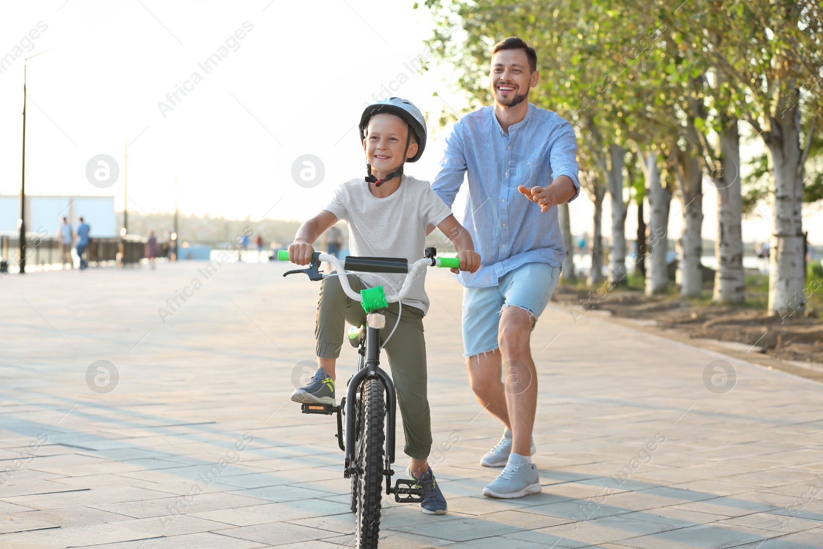 Photo of Father teaching son to ride bicycle on street