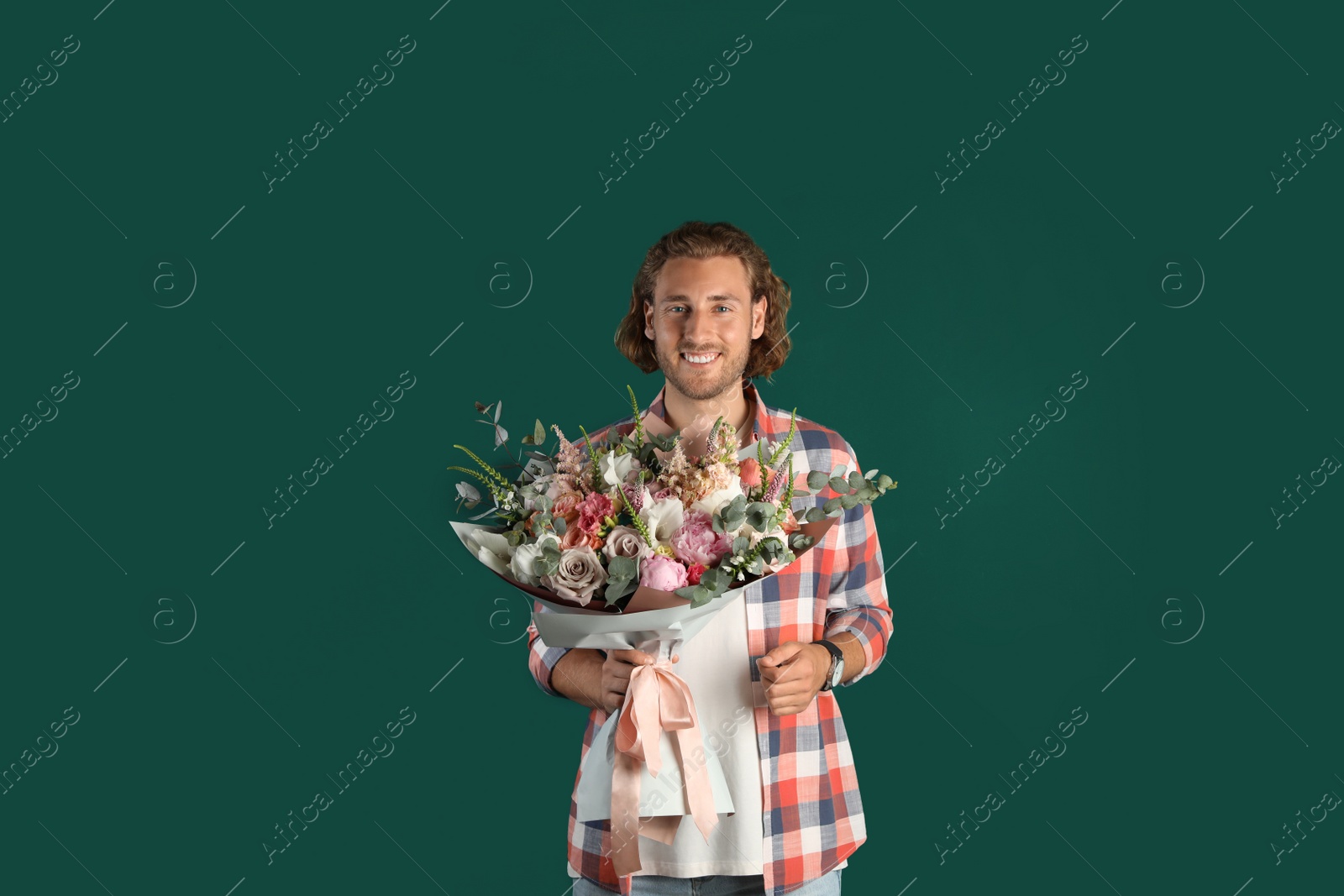 Photo of Young handsome man with beautiful flower bouquet on green background