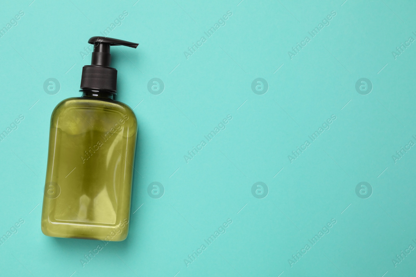 Photo of Bottle of face cleansing product on turquoise background, top view. Space for text