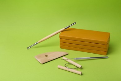 Photo of Clay and set of modeling tools on green background. Space for text