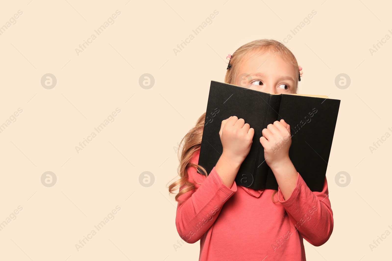 Photo of Little girl with book on light background. Space for text