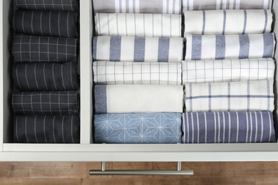 Photo of Open drawer with folded towels, top view. Order in kitchen