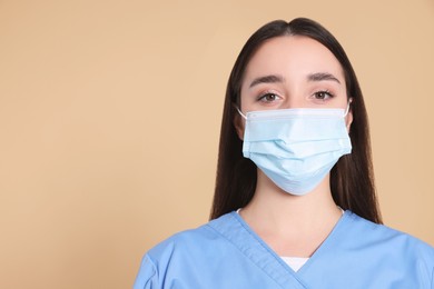Nurse wearing protective mask on light brown background, space for text