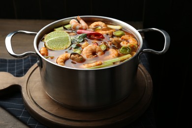 Photo of Saucepan with delicious Tom Yum soup on wooden table