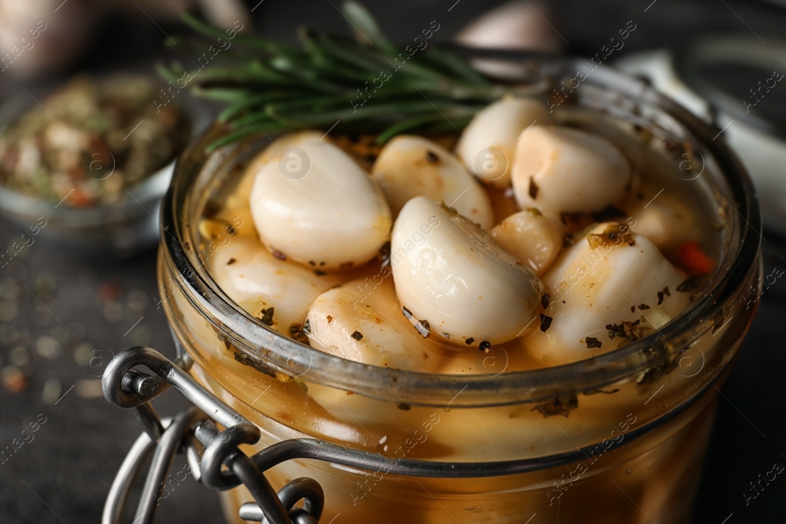 Photo of Preserved garlic in glass jar on table, closeup