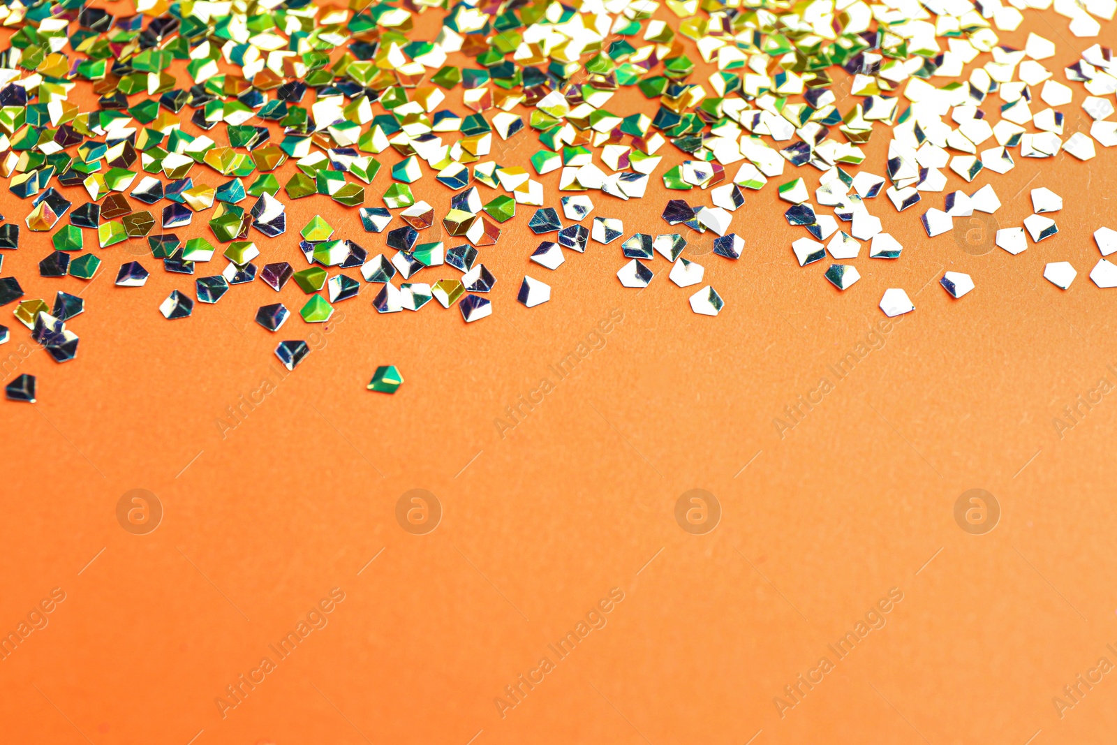 Photo of Shiny bright glitter on coral background. Space for text
