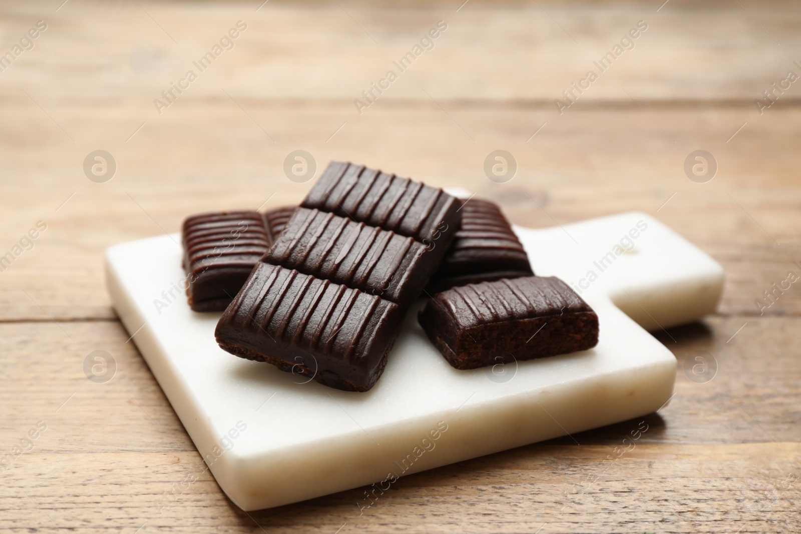 Photo of Board with delicious and healthy hematogen on wooden table, closeup