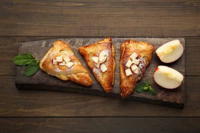Fresh tasty puff pastry with sugar powder, mint and apples served on wooden table, top view