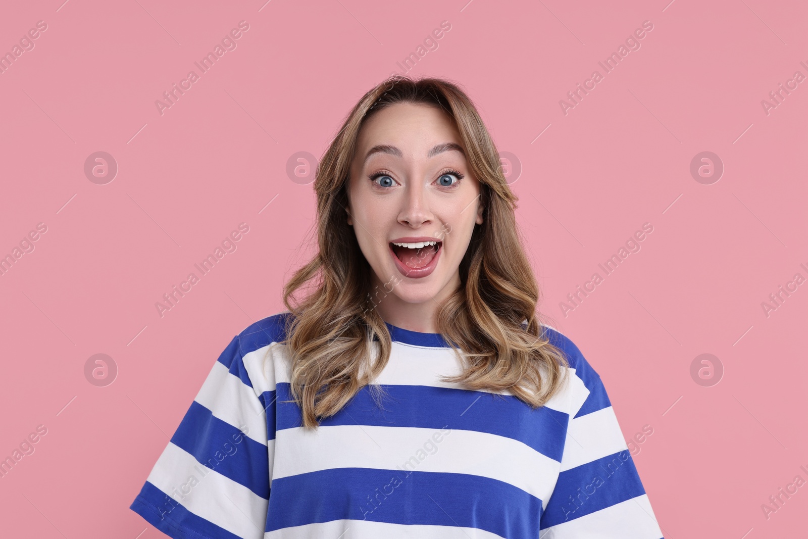 Photo of Portrait of happy surprised woman on pink background