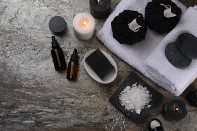 Photo of Flat lay composition with different spa products and burning candles on grey textured table. Space for text
