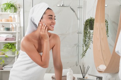 Photo of Beautiful young woman with perfect skin near mirror in bathroom. Facial wash
