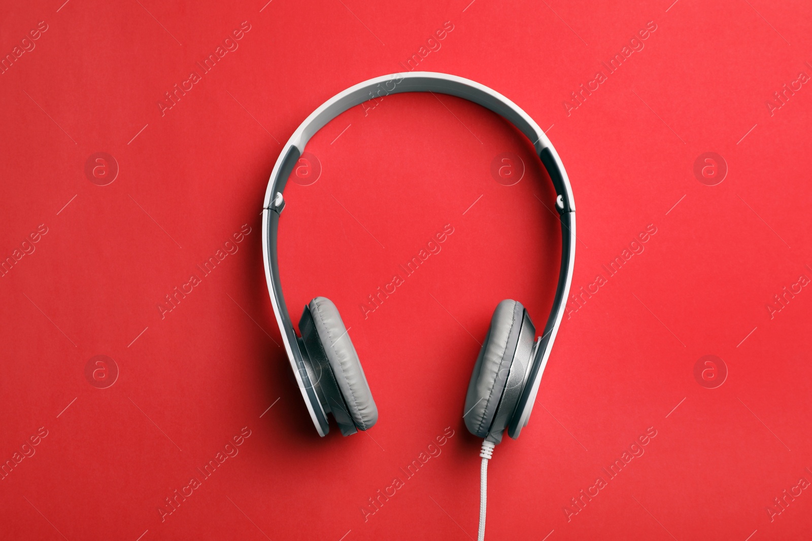 Photo of Stylish modern headphones with earmuffs on color background, top view