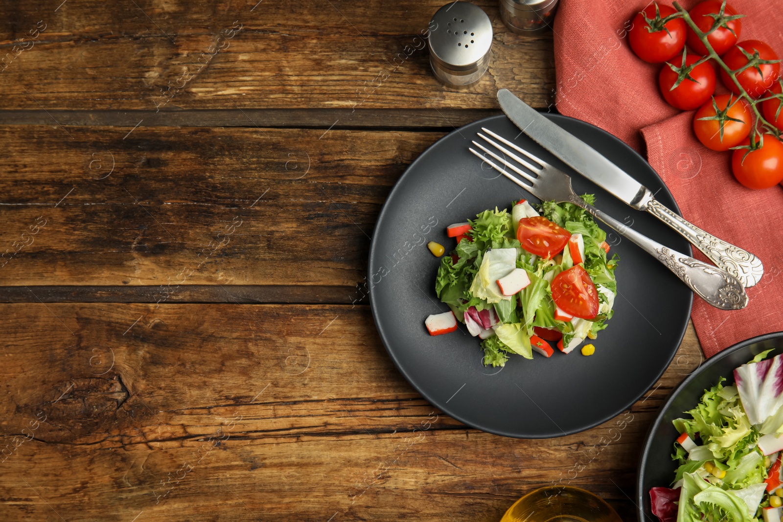 Photo of Delicious salad with crab sticks and tomatoes served on wooden table, flat lay. Space for text