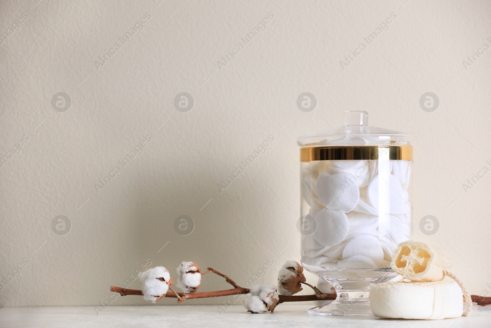 Photo of Jar with cotton pads on table against beige background. Space for text