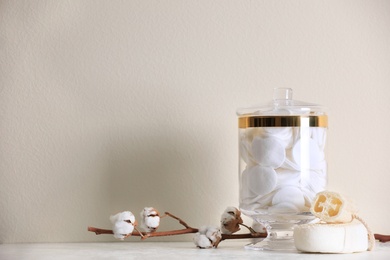 Photo of Jar with cotton pads on table against beige background. Space for text