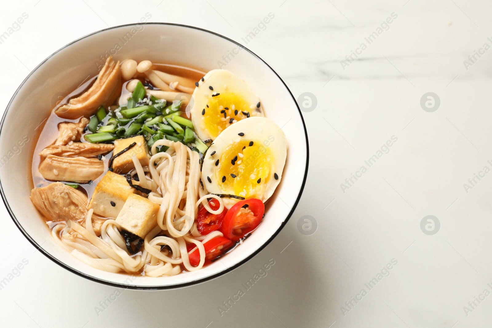 Photo of Bowl of delicious ramen on white marble table, above view. Noodle soup