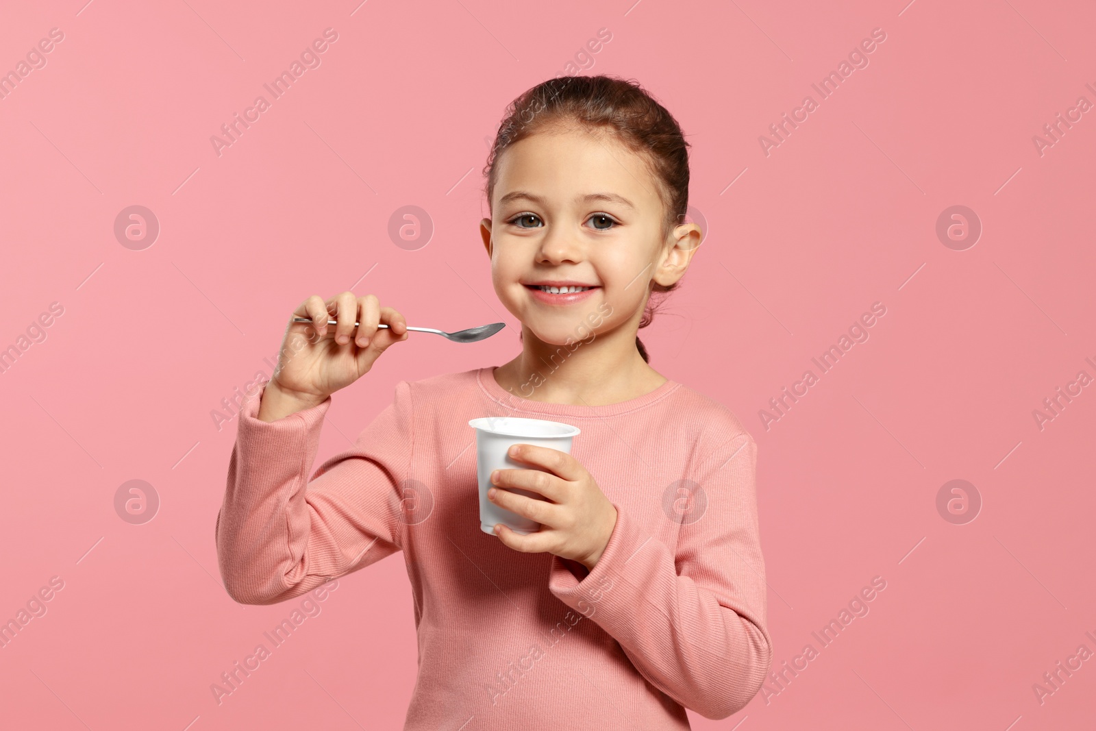 Photo of Girl with tasty yogurt on pink background