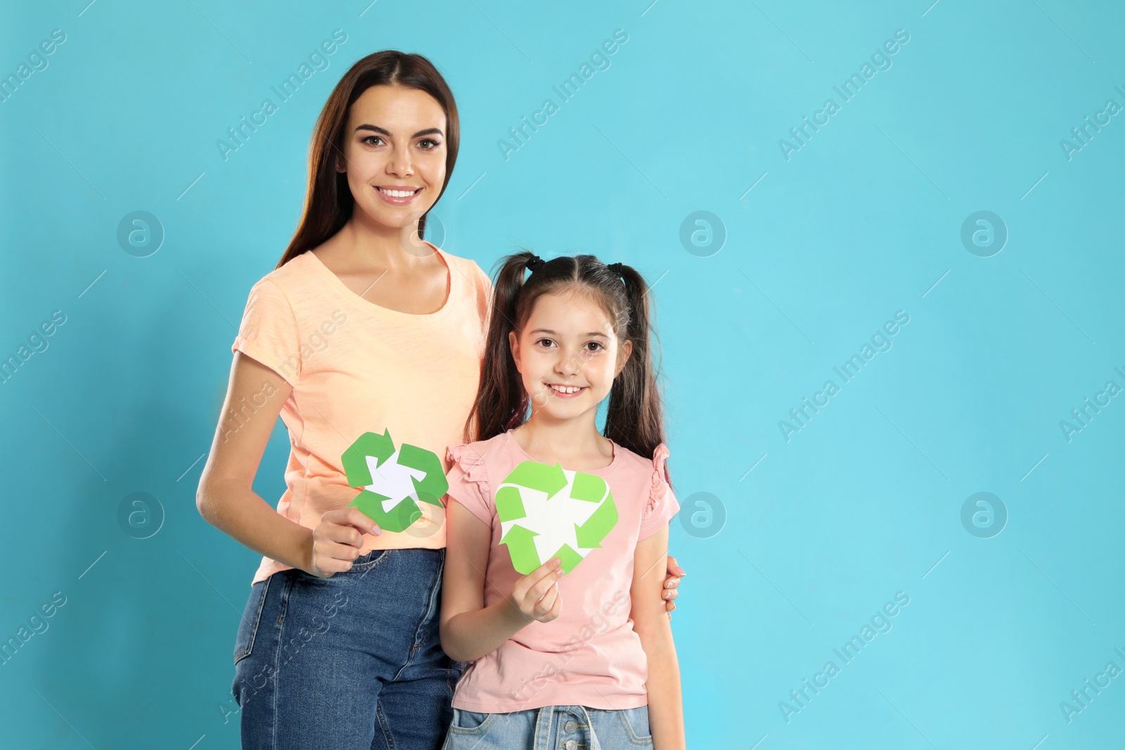 Photo of Mother and daughter with recycling symbols on blue background. Space for text