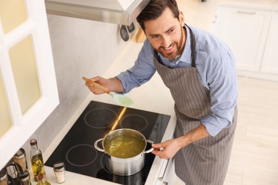 Man cooking delicious chicken soup in kitchen, above view