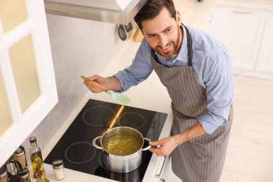 Photo of Man cooking delicious chicken soup in kitchen, above view