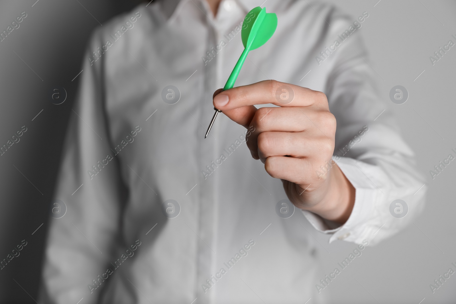 Photo of Businesswoman holding green dart on light background, closeup