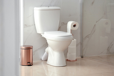 Photo of Modern toilet bowl with roll of paper in bathroom