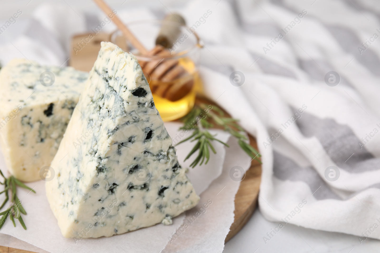 Photo of Tasty blue cheese with rosemary and honey on white table. Space for text