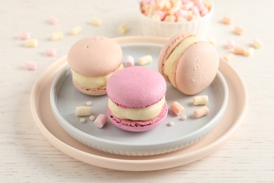 Photo of Delicious colorful macarons and marshmallows on white wooden table