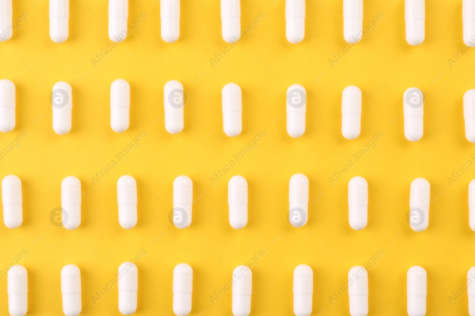 Photo of Many vitamin capsules on orange background, flat lay