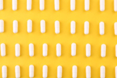 Photo of Many vitamin capsules on orange background, flat lay