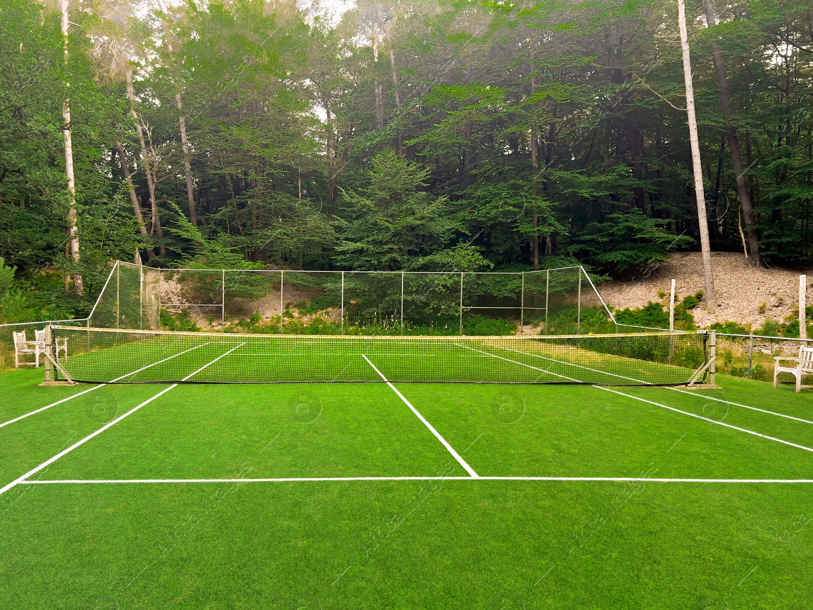 Photo of Tennis court with green grass and net outdoors