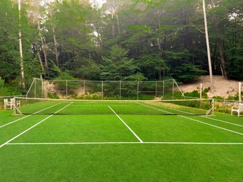 Photo of Tennis court with green grass and net outdoors