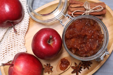 Photo of Delicious apple jam in jar, fresh fruits and spices on grey table, flat lay